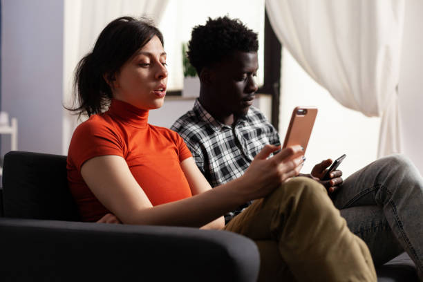 istock Close up of modern interracial couple using smartphones 1496092609