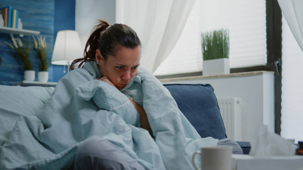 istock Person with disease feeling cold with blanket and pillow on couch 1496096013