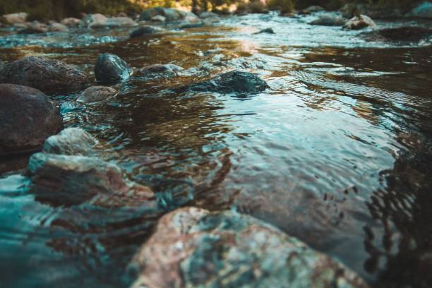 istock a river that has water rushing over rocks on it with the sun rising behind the 1496097896