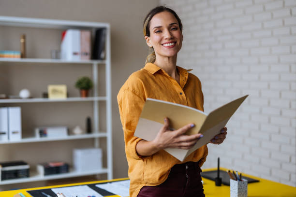 A Happy Beautiful Blonde Businesswoman Looking At Camera While Holding A Notebook