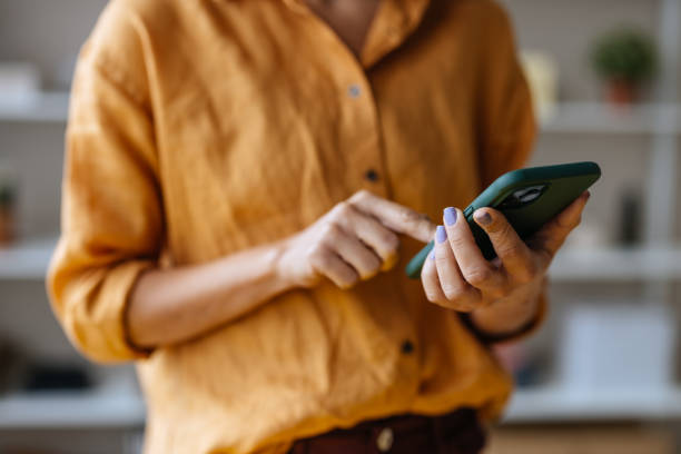 una mujer de negocios irreconocible que usa su teléfono móvil mientras trabaja en la oficina - unrecognizable person laptop holding women fotografías e imágenes de stock