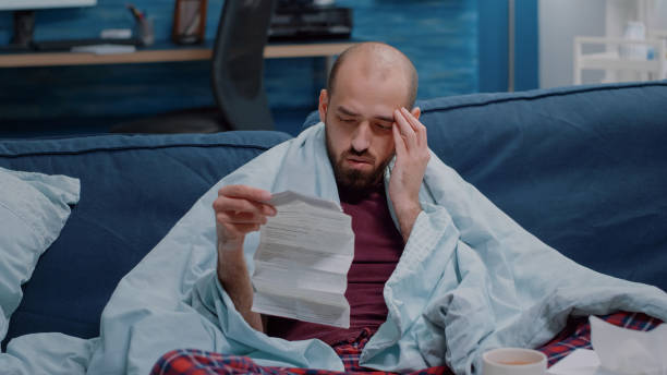 istock Unwell man with headache looking at medicine leaflet 1496098588