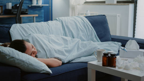 istock Sick woman laying on couch with blanket feeling cold 1496098834