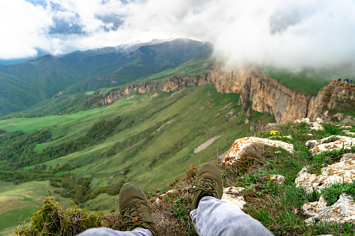A man sits in the mountains near a cliff