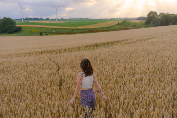 Woman walking among wheat field crop and looking at a distant view