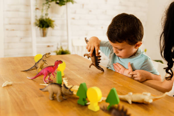 istock Curious little boy playing with dinosaur toy on the table 1496109316