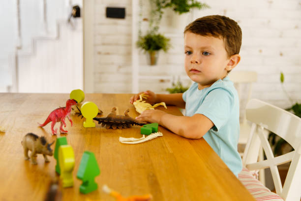 istock Curious little boy playing with dinosaur toy on the table 1496109336