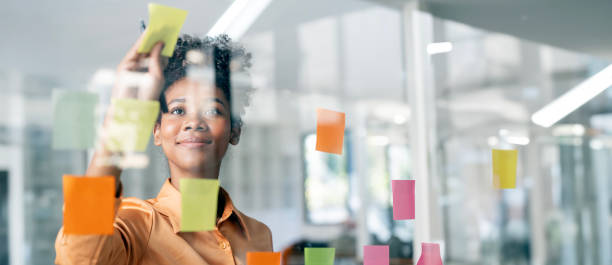 istock Happy black businesswoman planning new project with sticky note in a creative office 1496111265
