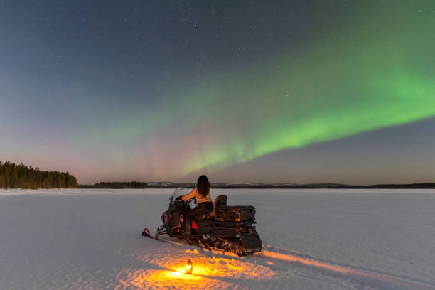 istock Woman on the snowmobile with aurora borealis 1496111455
