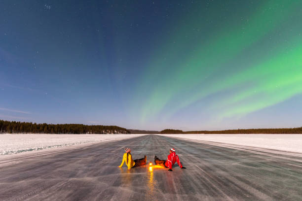 istock Two poeple sitting on ice under northern lights 1496111497
