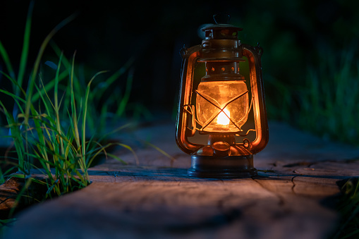 the antique oil lamp on the old wooden floor in the forest at night camping atmosphere