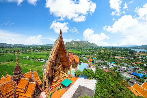 Wat Tham Sua on top hill with green rice fields and blue sky in Kanchanaburi Province Thailand.