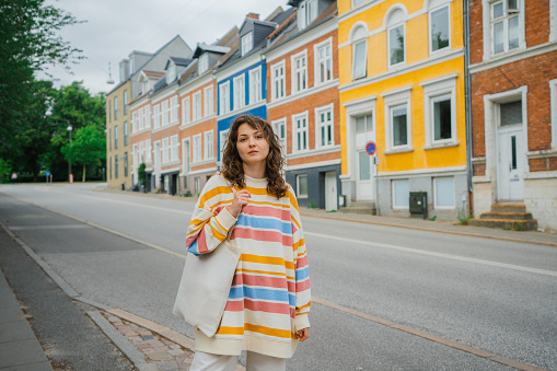 Young Caucasian woman standing on the background of colourful building in Gothenburg