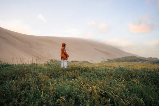 Young Caucasian woman walking  near the big sand dunes in Denmark  during extreme weather