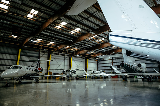 Inside of a massive hangar, several aircrafts are parked.