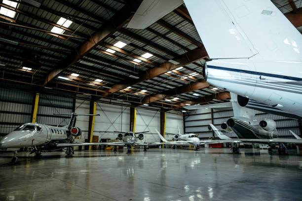 A giant hangar with a few aircrafts parking in it Inside of a massive hangar, several aircrafts are parked. airplane hangar stock pictures, royalty-free photos & images