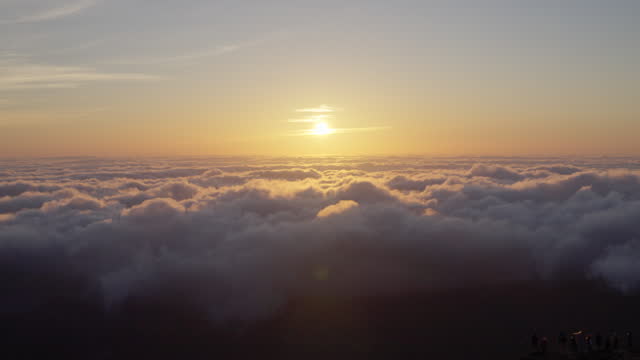 Beautiful view of sun setting above sea of clouds on top of mountain