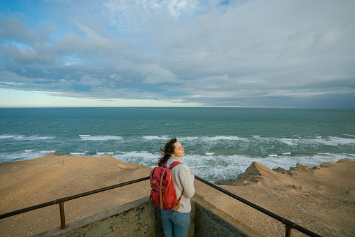 Young Caucasian woman standing on the top of Rubjerg Knude lighthouse and looking at view