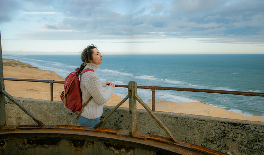 Young Caucasian woman standing on the top of Rubjerg Knude lighthouse and looking at view