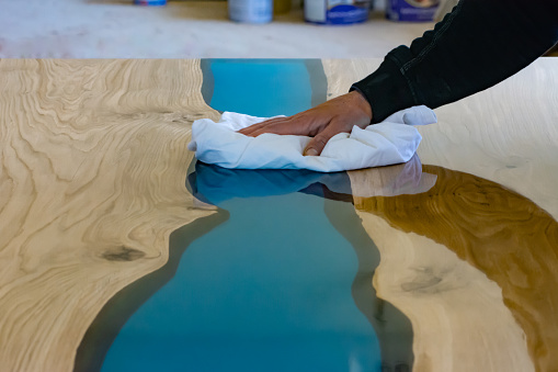 Wiping the remains of the polishing paste on the oak and epoxy resin table