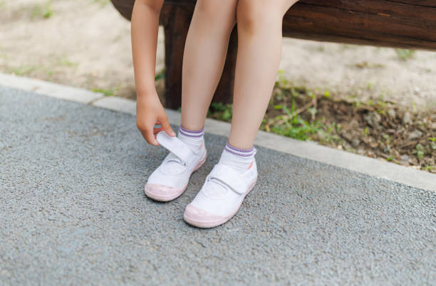 istock Little girl adjusts canvas shoes 1496117639