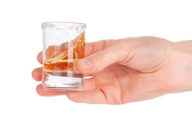 istock Man's hand holding a glass with tequila 1496119925