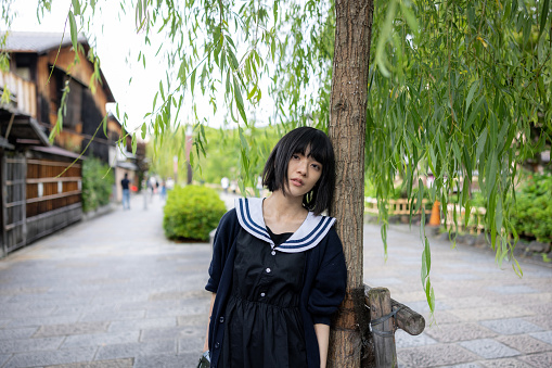 Portrait of woman leaning on willow tree in Gion, Kyoto, Japan