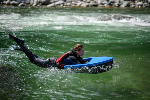 Young woman hydrospeeding in alpine river. River Sesia in Valsesia, Piedmont, Italy.
