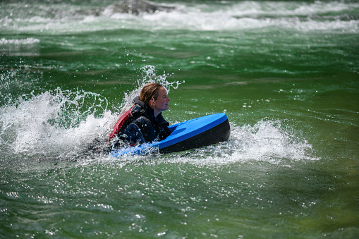 Young woman hydrospeeding in alpine river. River Sesia in Valsesia, Piedmont, Italy.