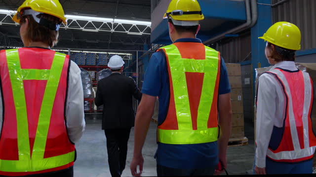 Group asian team manager visit and employee walking and inspection distribution storehouse in warehouse factory, supervisor or boss and worker checking supply and stock, slow motion, industry concept.