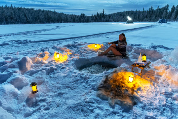 Scandinavian woman relaxing outside glass igloos after cold bath Beautiful woman in scandinavian clothes relaxes and drinks wine after a cold bath in a hole of a frozen lake, Sweden swedish sauna stock pictures, royalty-free photos & images