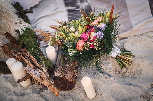 Wedding bouquet in boho style laying on the sand near textured tree bark
