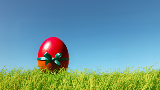 Red easter egg with bow in the grass