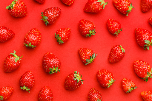 Top view of fresh strawberries on red background