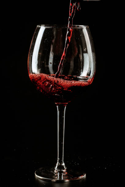 istock Red wine being poured in a wine glass on a dark background 1496131954