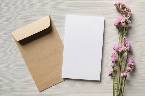 istock White blank greeting or invitation card and envelope with pink flowers decoration on white wooden background. Mock up presentation. 1496132081
