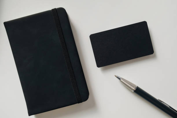 istock Black blank business card mockup with notebook and pen on white background. Mock up presentation. 1496132089