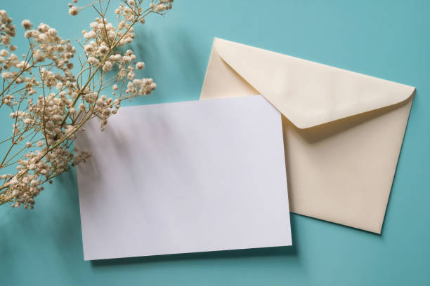 istock White blank greeting or invitation card and envelope gypsy flower decoration on blue background. Mock up presentation. 1496132115