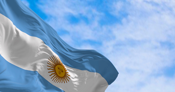 Argentina national flag fluttering in the wind on a sunny day. Three equal blue and white horizontal bands with the Sun of May in the center. 3d illustration render. Selective focus