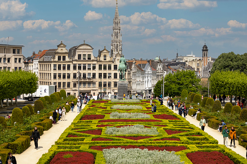 Brussels, Belgium - May 18, 2023: Mount of the Arts (Mont des Arts), view of colorful garden, Equestrian Statue of Albert I and spire of Town Hall