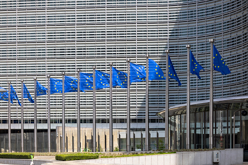 Brussels, Belgium - May 18, 2023: Blue flags of Europe in front of Berlaymont, seat of the European Commission. The building is located at the Robert Schuman Roundabout