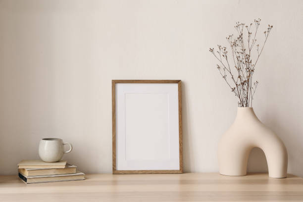 istock Elegant boho still life. Modern vase with dry grass on table, desk. Empty wooden picture frame mockup. Cup of coffee, books. Artistic poster display. Minimal home interior. Home office desk. 1496140644
