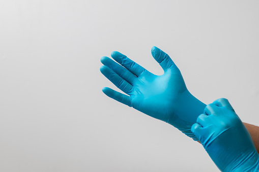 Male hand wearing blue latex gloves, medical, protective, white background