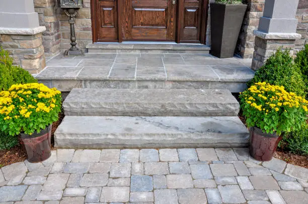 Photo of Front entrance luxury hardscaping with natural stone steps and wet laid flagstone.