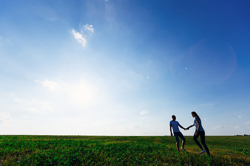 silhouette couple holding hands and walking on blue sky background.