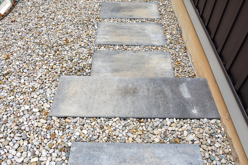 Precast concrete steps, paver stepping stones and pea gravel run along the side of a home, providing a safe transition to sideyard to the backyard below.