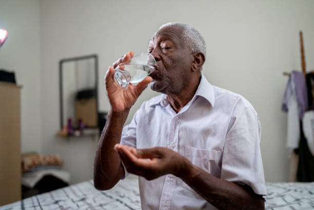 istock Senior man taking pills in bed at home 1496145218