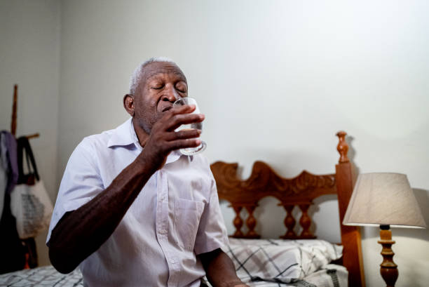 istock Senior man drinking water in bed at home 1496145220
