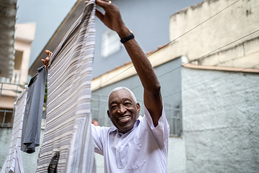 Portrait of a senior man hanging clothes to dry in the back yard