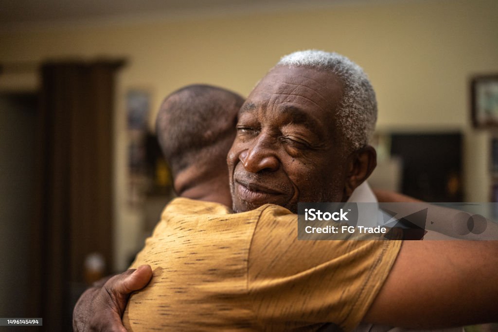Bonding moment of father and son embracing and giving emotional support at home Senior Adult Stock Photo